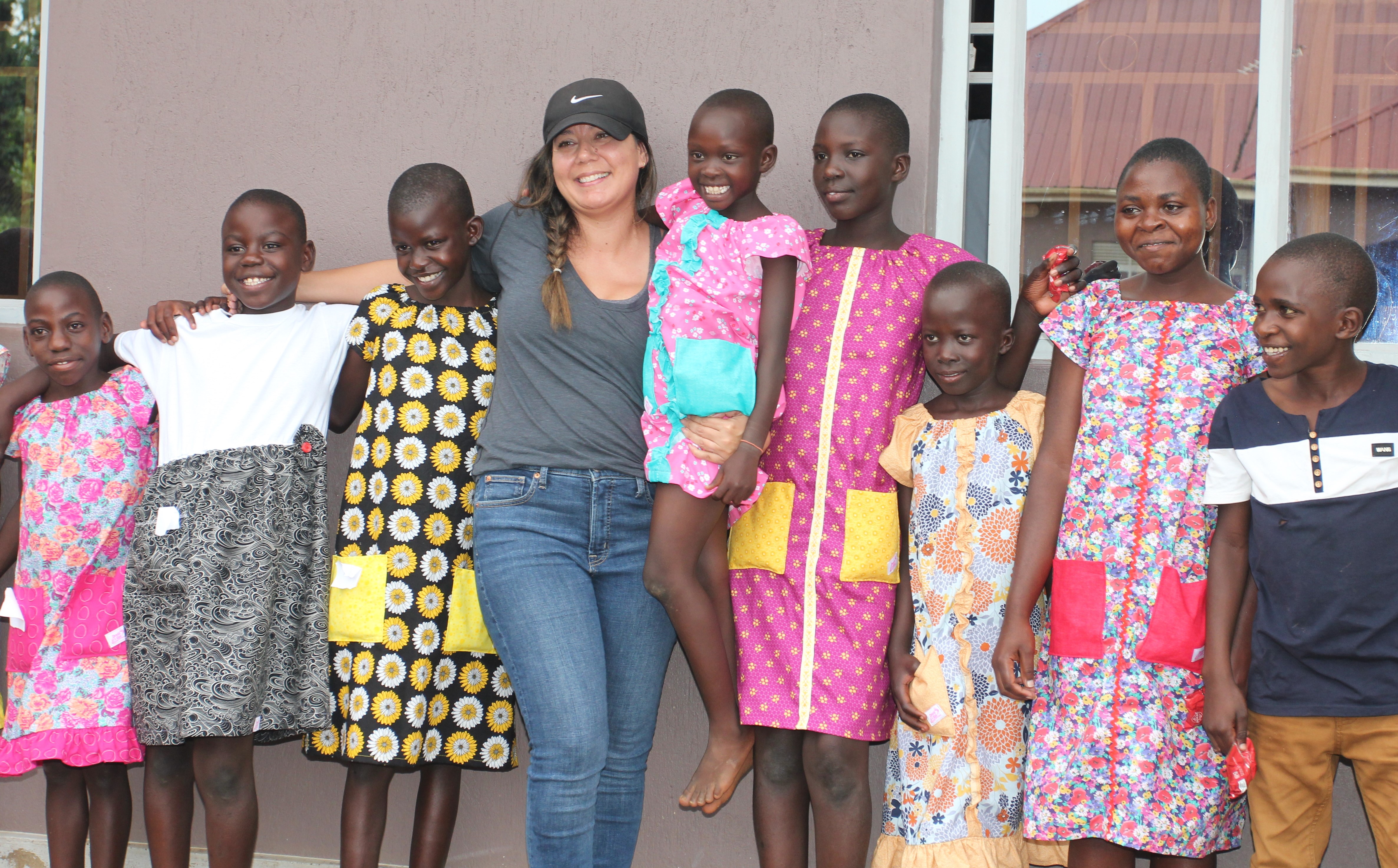 Erica Estrella stands with children who received Dress a Girl Around the World dresses
